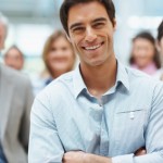 Confident smiling business man with his team at the back